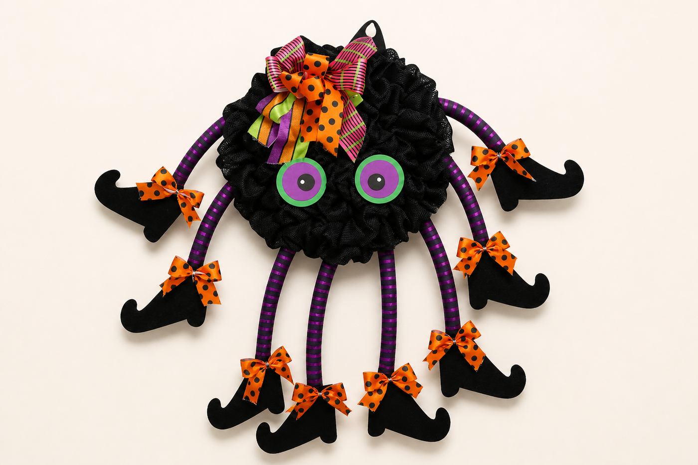 Complete TangleToes black mesh spider wreath shown front-facing with green purple eyes eight striped legs bows and curled boots