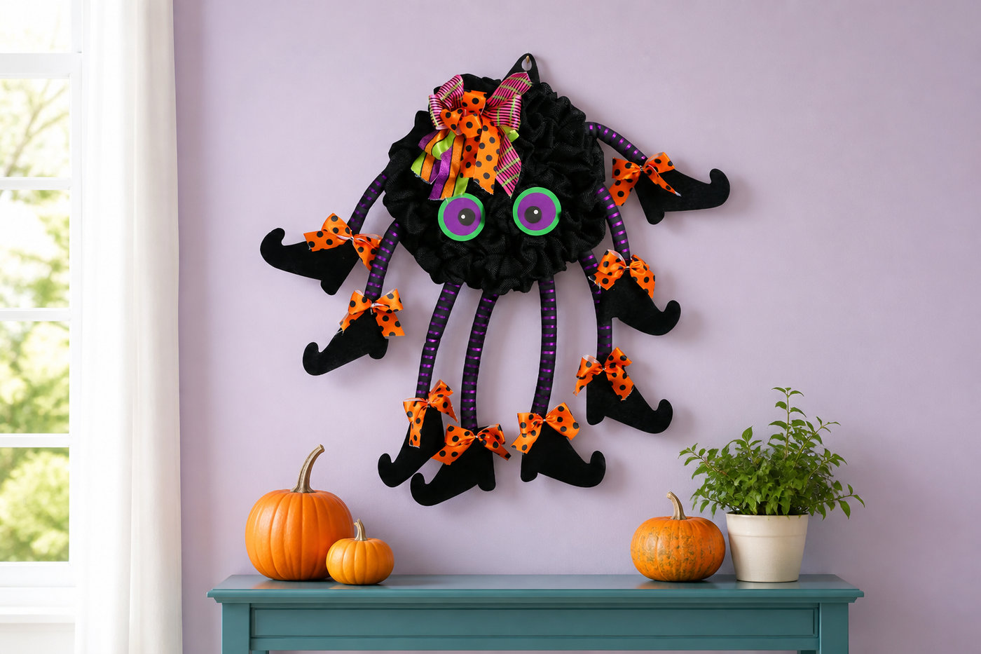 TangleToes colorful spider wreath displayed on a lavender interior wall above a teal console