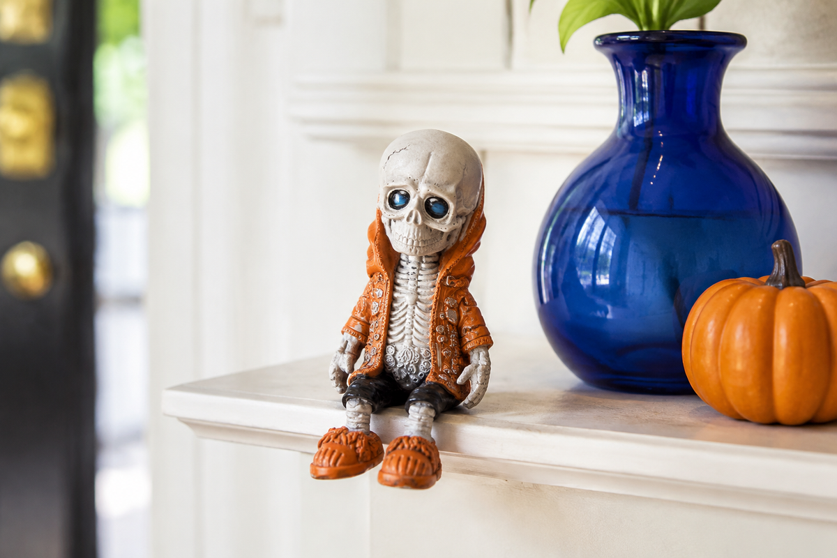 Orange D ShelfBones seated skeleton figurine beside a cobalt vase and pumpkin