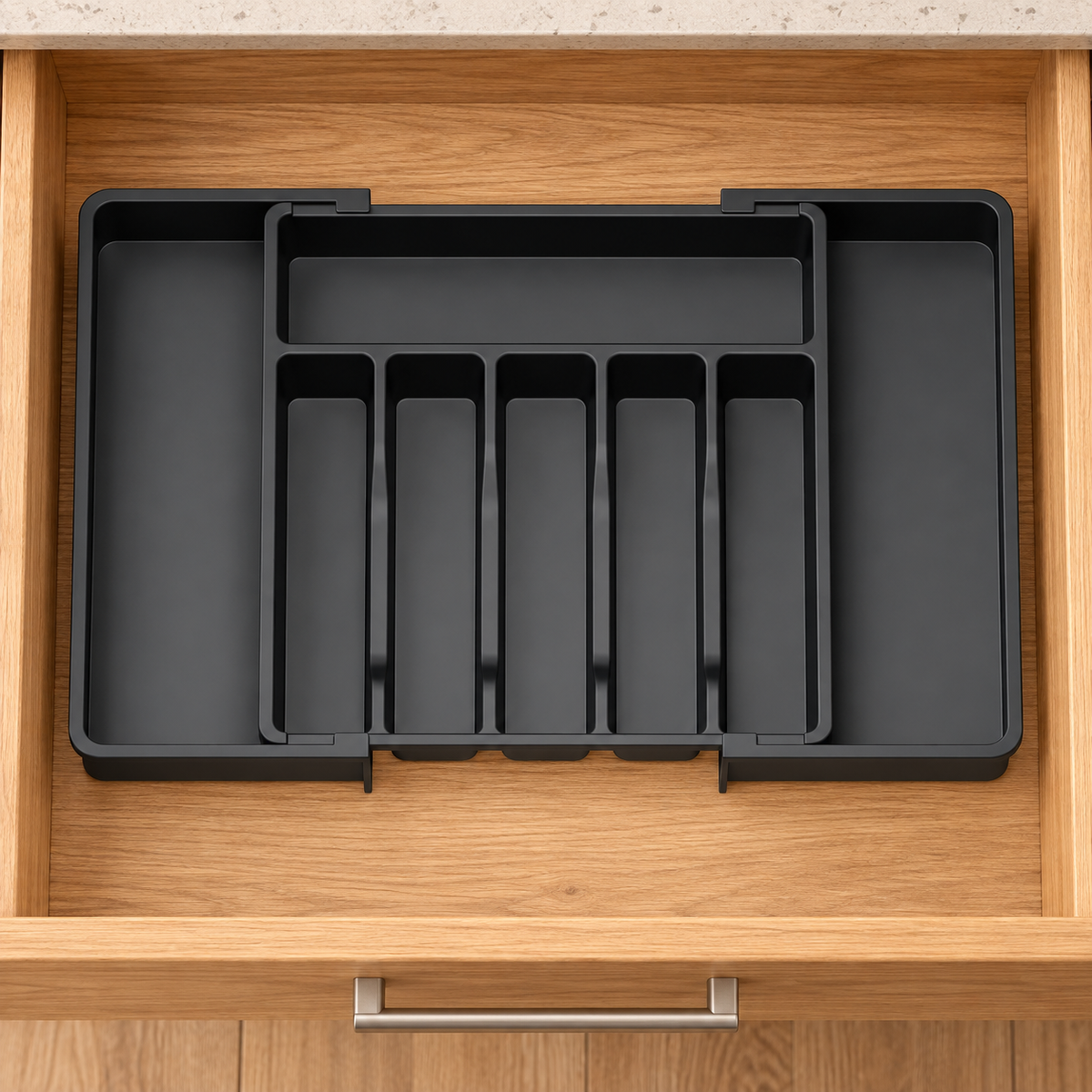Empty black DrawerEase expandable organizer with eight compartments in an oak kitchen drawer