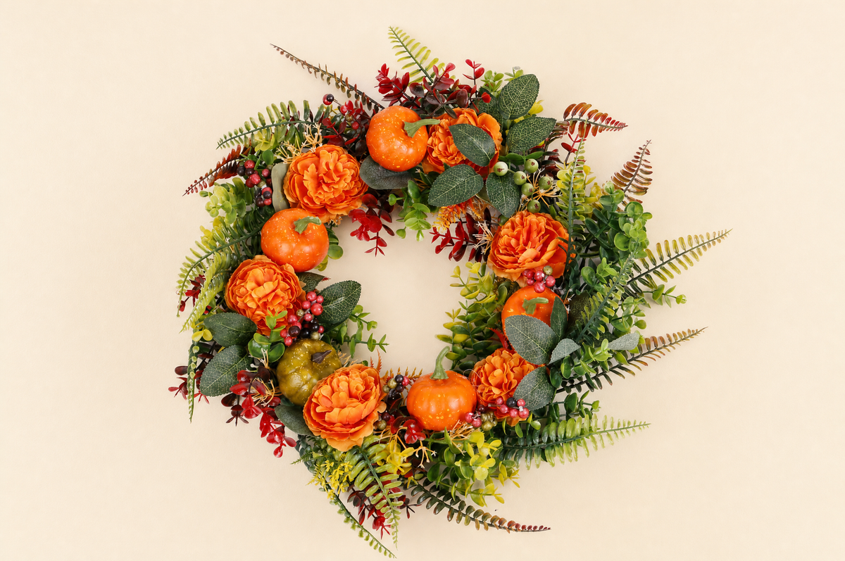 Wide secondary wall view of the EmberLeaf artificial pumpkin wreath with orange flowers, berries and fern foliage.